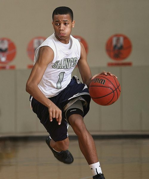 Energetic basketball player in mid-dribble on an indoor court.