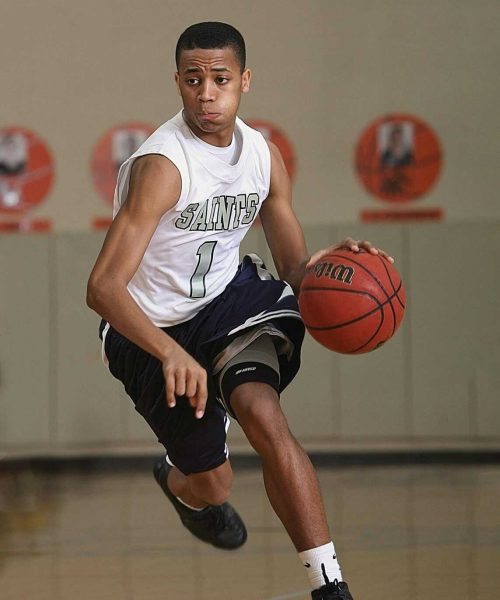 Energetic basketball player in mid-dribble on an indoor court.